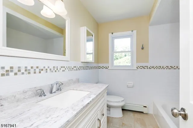 a bathroom with a granite countertop toilet a sink and a mirror