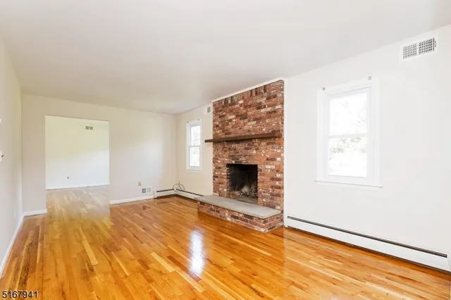 a view of empty room with fireplace and wooden floor