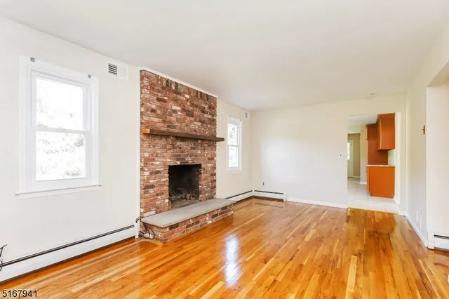 a view of empty room with wooden floor and fireplace