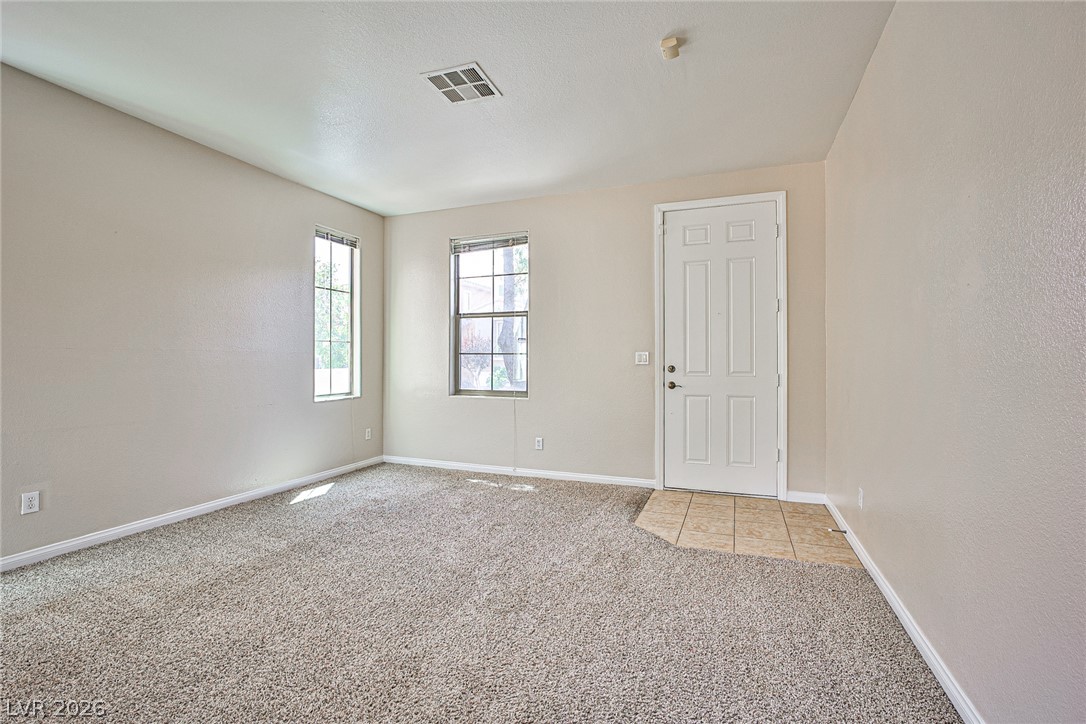 A tiled entryway transitions smoothly into carpeted flooring under tall ceilings with natural light.