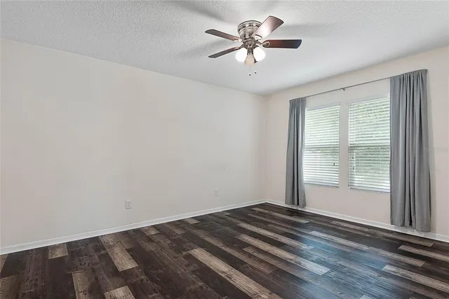 an empty room with a chandelier fan and windows