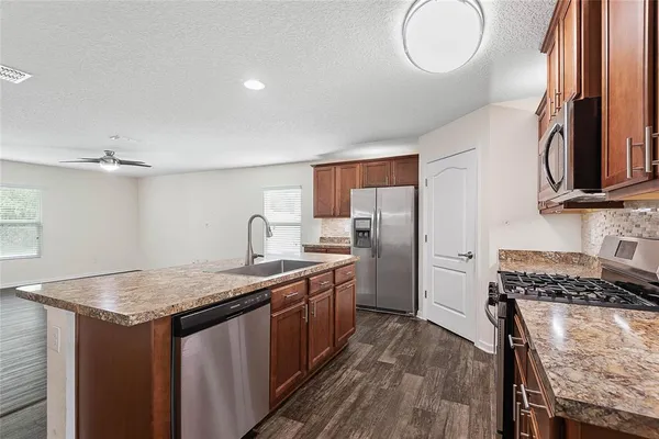 a kitchen with granite countertop a sink a counter space and stainless steel appliances