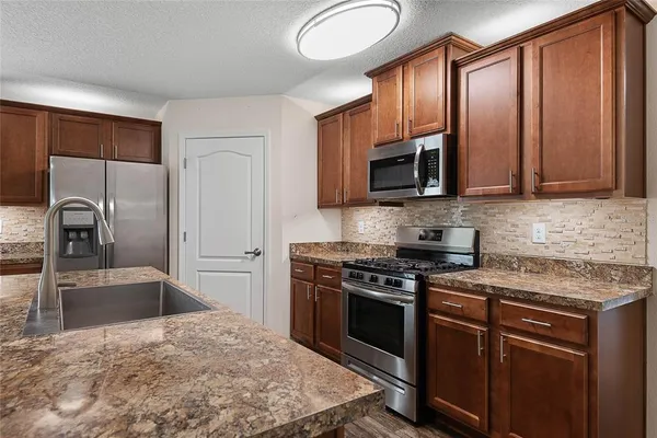 a kitchen with stainless steel appliances granite countertop a stove a sink and a microwave