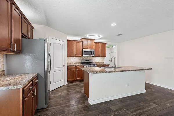 a kitchen with stainless steel appliances granite countertop a refrigerator a stove a sink and a microwave