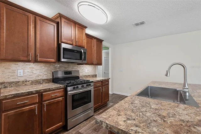 a kitchen with granite countertop wooden cabinets stainless steel appliances and a sink