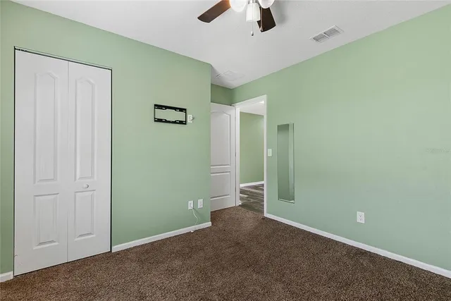 an empty room with ceiling fan and window