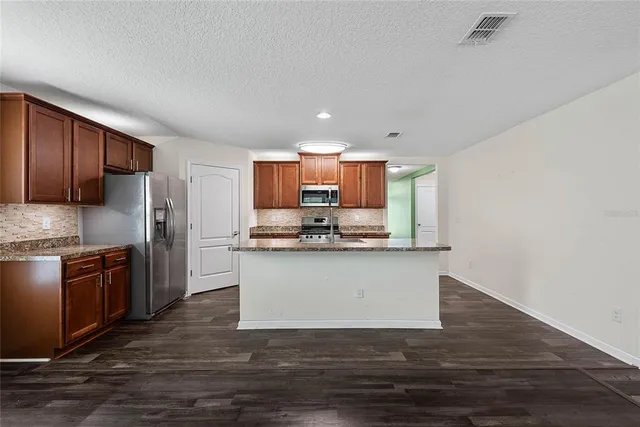 a kitchen with granite countertop a stove top oven and refrigerator