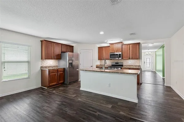 a kitchen with stainless steel appliances kitchen island granite countertop a stove a sink and a refrigerator