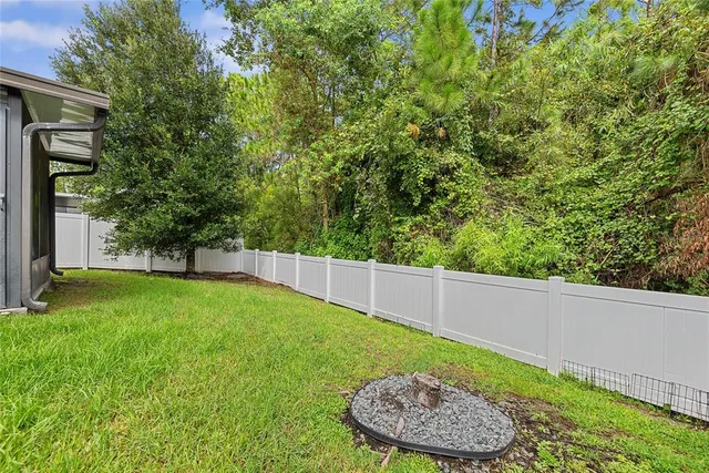 a view of a backyard with table and chairs plants and large tree