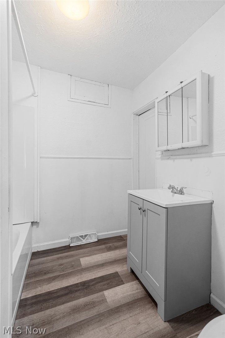 2387 29th Street Southwest Akron, OH 44314 - Photo 12 of 24 Full bathroom featuring vanity, a textured ceiling, dark wood-type flooring, and bathing tub / shower combination
