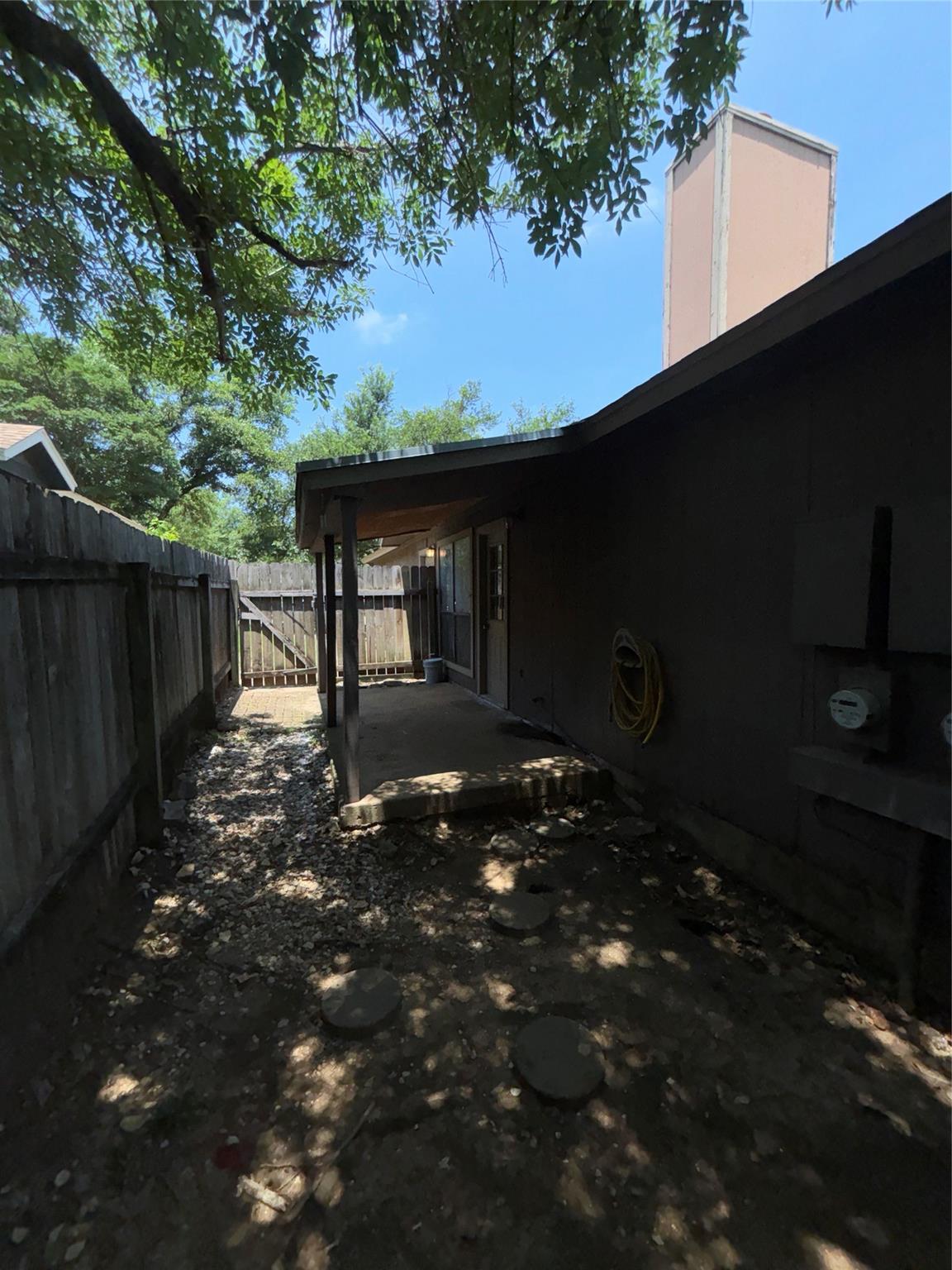2033 Redwing Way Round Rock, TX 78664 - Photo 12 of 13 Covered patio with a concrete slab, framed by a wood fence and mature trees