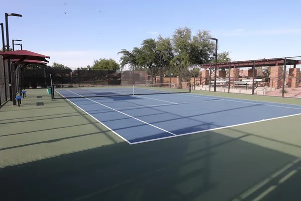 a view of a tennis ground with large trees