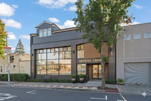 a view of a white building among the street with palm trees