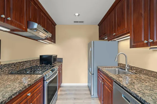 a kitchen with stainless steel appliances granite countertop a sink stove and refrigerator