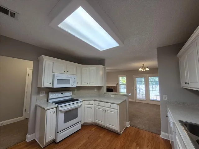 a kitchen with granite countertop white cabinets and white appliances