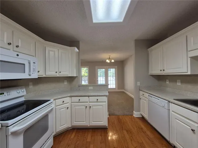 a kitchen with granite countertop white cabinets and white appliances
