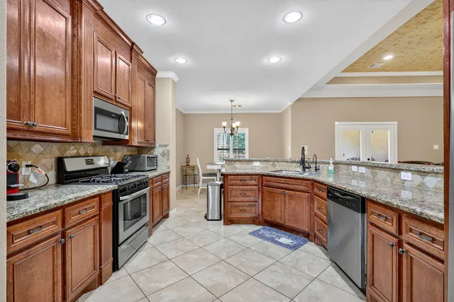 a large kitchen with stainless steel appliances granite countertop a sink and dishwasher a stove top oven with wooden floor