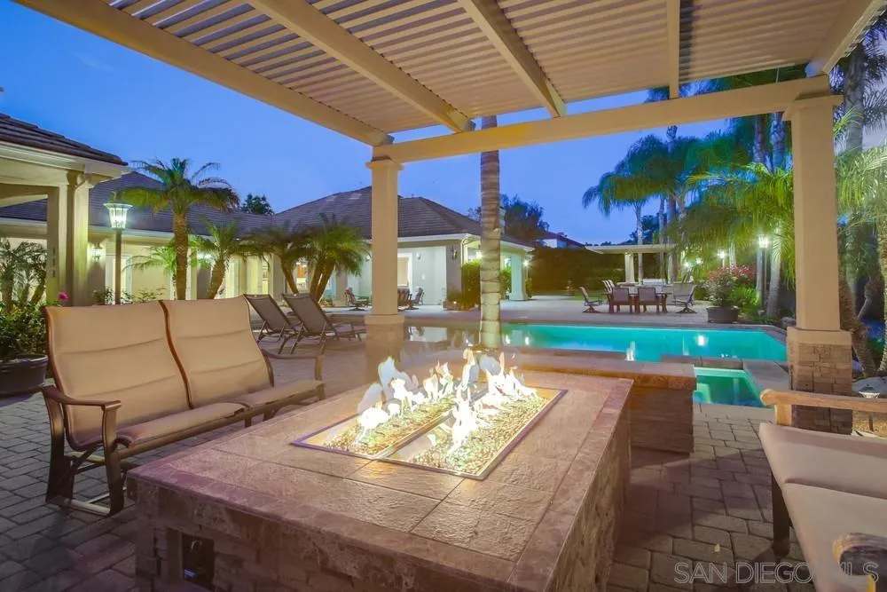 6867 Poco Lago Rancho Santa Fe, CA 92067 - Photo 13 of 52 a view of a patio with a table and chairs under an umbrella