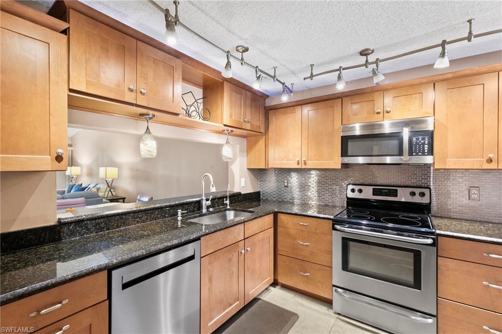 236 Pebble Beach Circle, Unit A202 Naples, FL 34113 - Photo 7 of 25 a kitchen with granite countertop a sink stainless steel appliances and cabinets