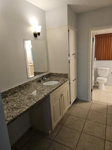 a bathroom with a granite countertop sink and a toilet