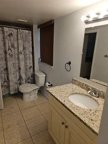 a bathroom with a granite countertop sink a toilet and a mirror