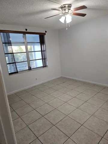 an empty room with windows and ceiling fan