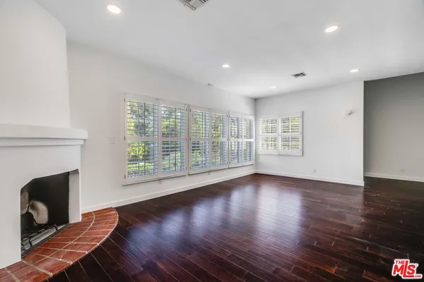 a view of an empty room with wooden floor and a fireplace