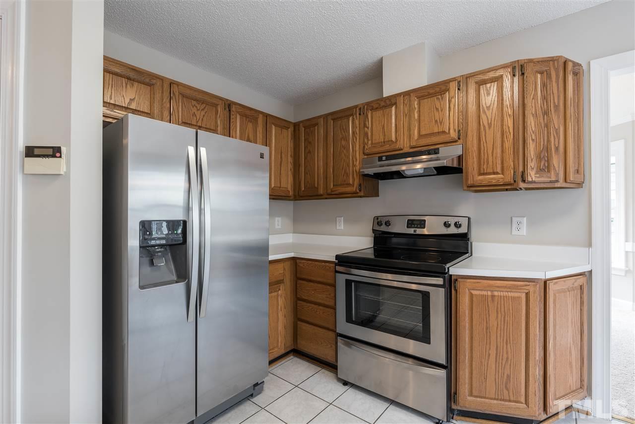 4237 Dinwiddie Court Raleigh, NC 27604 - Photo 11 of 25 a kitchen with stainless steel appliances granite countertop wood cabinets a refrigerator and a stove top oven