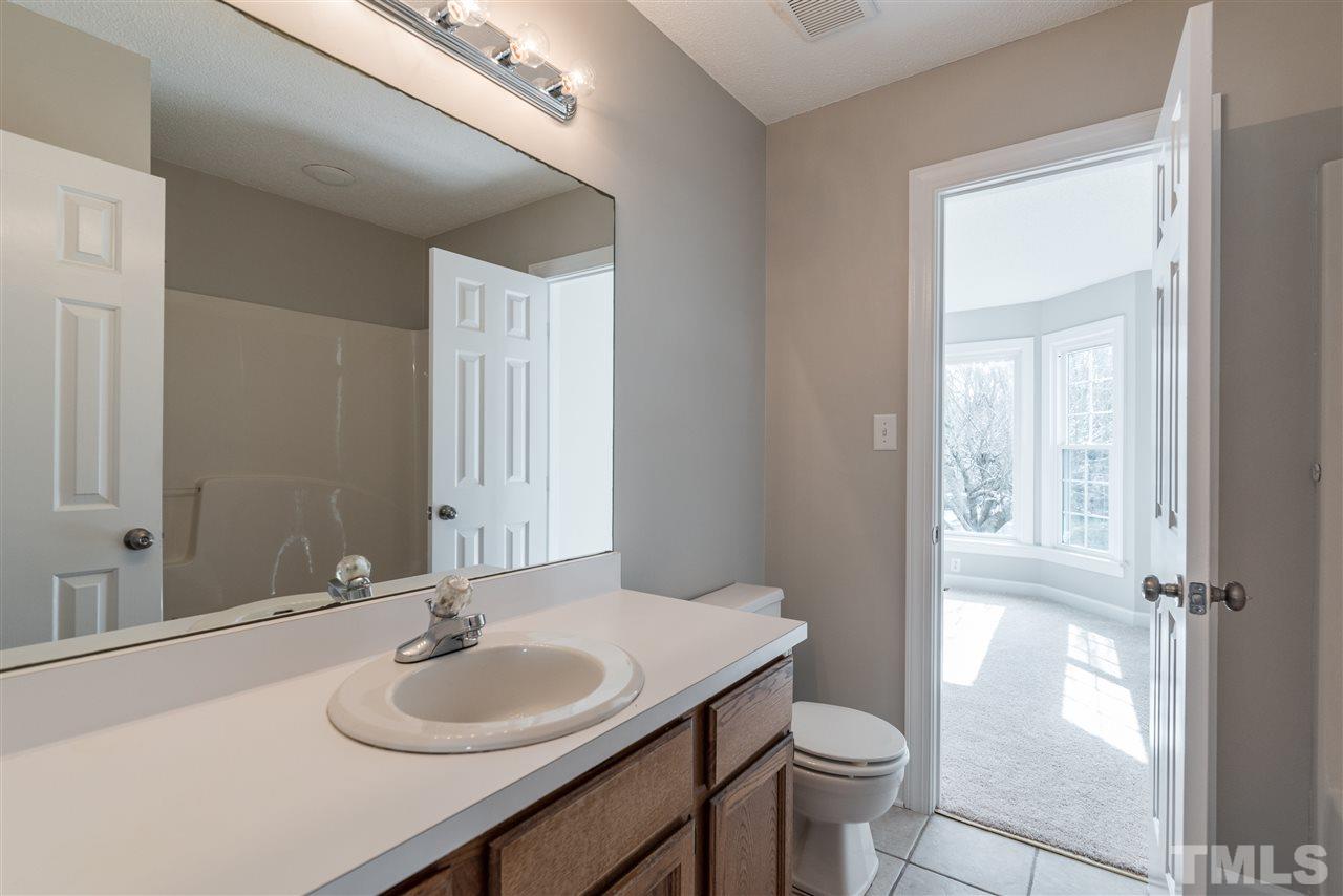 4237 Dinwiddie Court Raleigh, NC 27604 - Photo 22 of 25 a bathroom with a granite countertop sink toilet a mirror and a shower