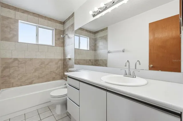 a bathroom with a granite countertop sink a toilet a mirror and bathtub