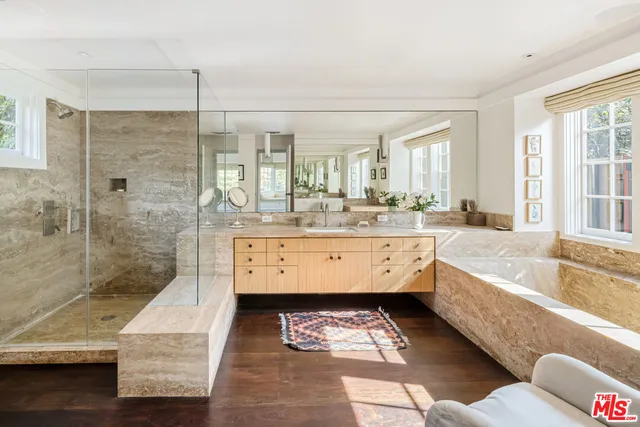 a bathroom with a tub a double vanity sink and a shower