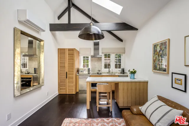 a living room with stainless steel appliances furniture a chandelier a rug and a large window