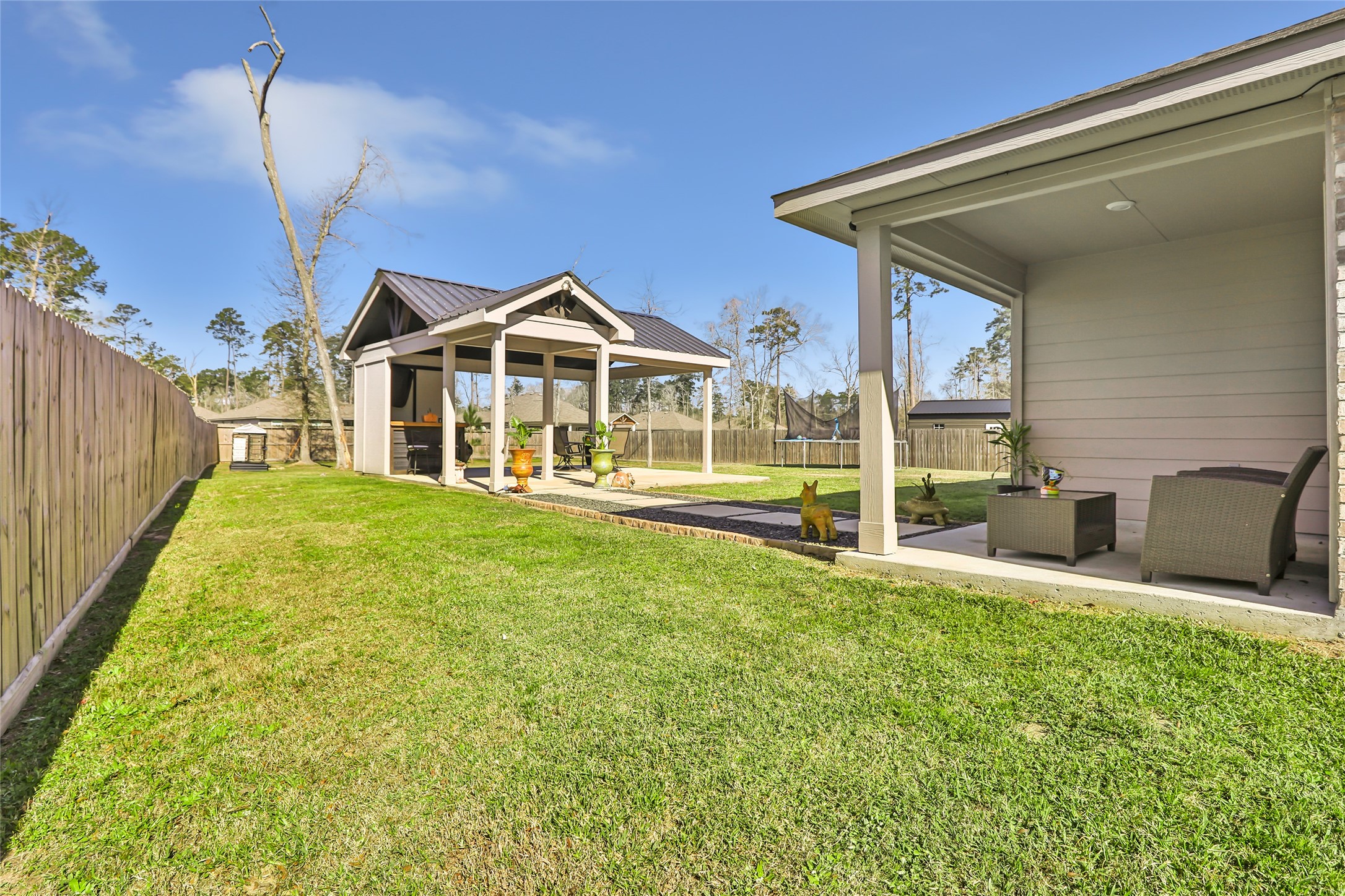 811 Republic Road New Caney, TX 77357 - Photo 6 of 37 This photo shows a well-maintained backyard featuring a covered patio with seating, a separate covered structure, and a spacious lawn. Ideal for outdoor relaxation and entertaining.