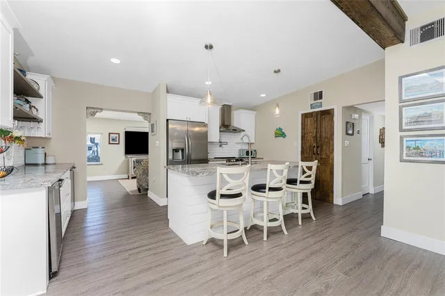 a kitchen with stainless steel appliances a dining table chairs refrigerator and sink