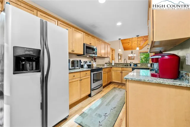 a kitchen with stainless steel appliances granite countertop a refrigerator a stove and a sink with wooden floor