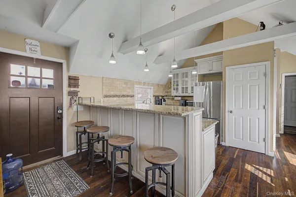 a kitchen with kitchen island granite countertop wooden floors and white cabinets