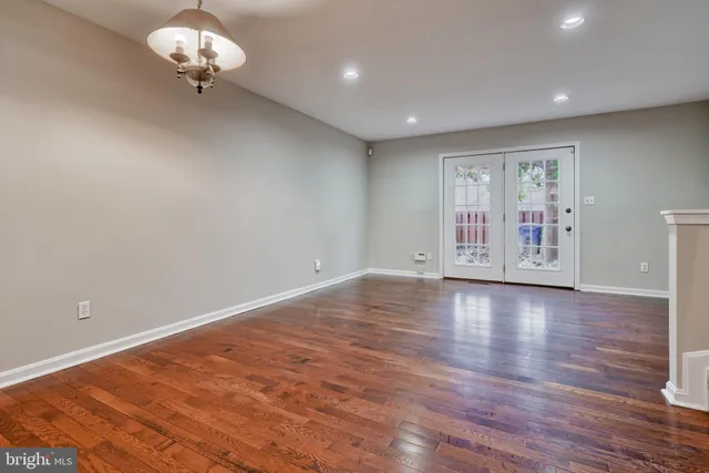 a view of an empty room with wooden floor and a large window