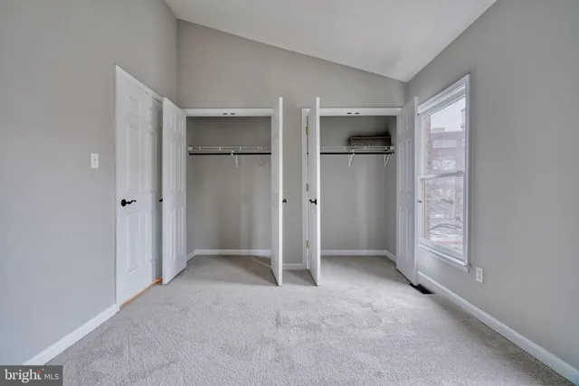 a view of an empty room with kitchen and a window