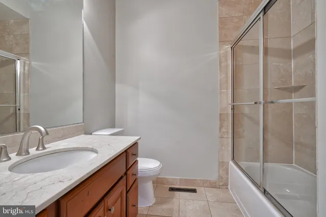 a bathroom with a granite countertop sink a toilet and shower
