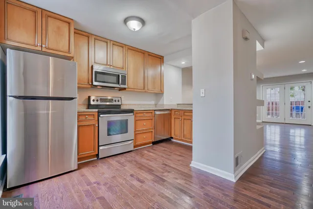 a kitchen with wooden floors and stainless steel appliances