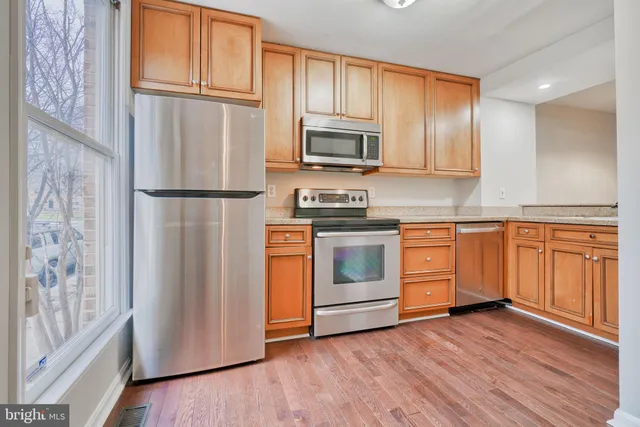 a kitchen with stainless steel appliances white cabinets and wooden floors