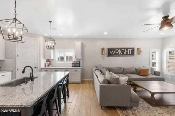 a living room with furniture a chandelier and kitchen view
