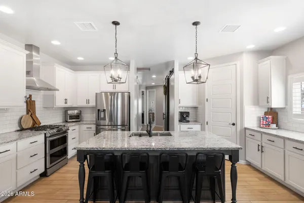 a kitchen with stainless steel appliances kitchen island granite countertop a stove a sink and a refrigerator
