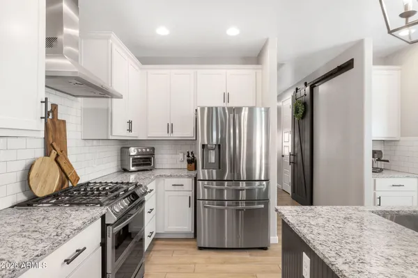a kitchen with granite countertop kitchen island stainless steel appliances a refrigerator cabinets and wooden floor