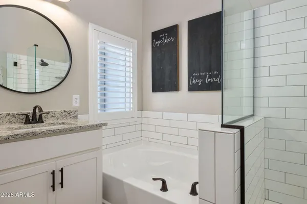 a bathroom with a granite countertop sink a mirror and a bathtub