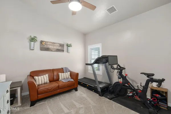 a living room with furniture a flat screen tv and a gym cycle