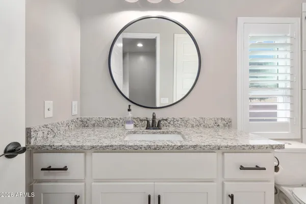 a bathroom with a granite countertop sink and a mirror