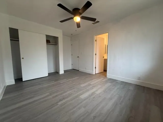 an empty room with wooden floor and a ceiling fan