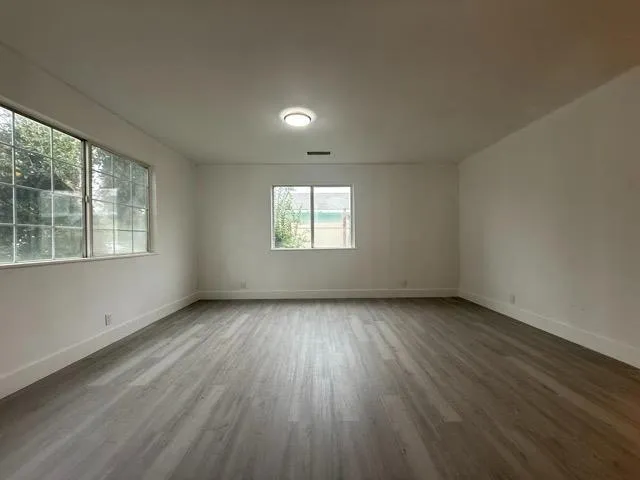 a view of an empty room with wooden floor and a window