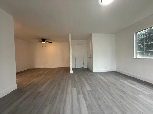 an empty room with wooden floor and windows
